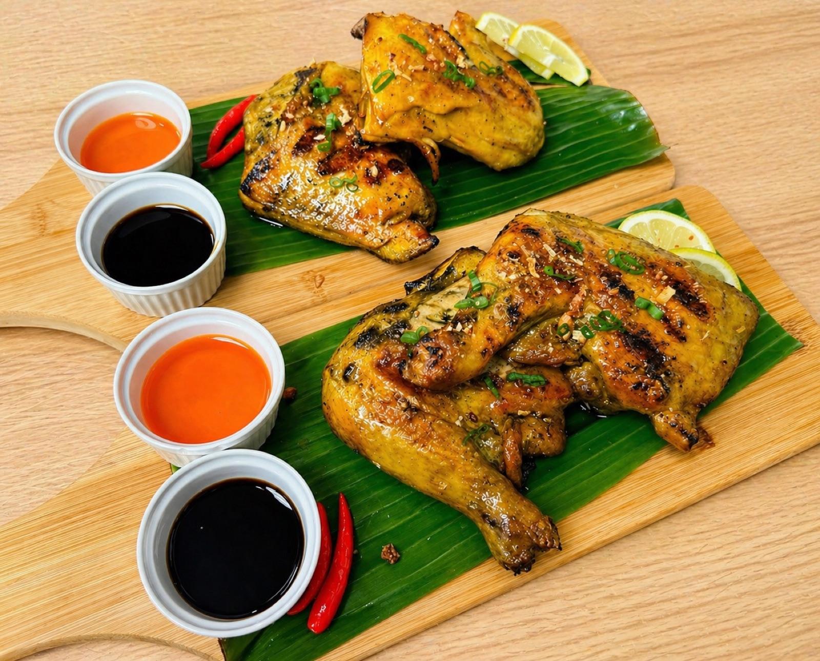 Two pieces of charcoal-grilled chicken inasal on a banana leaf with dipping sauces — a signature dish at Island Pacific Kitchen.